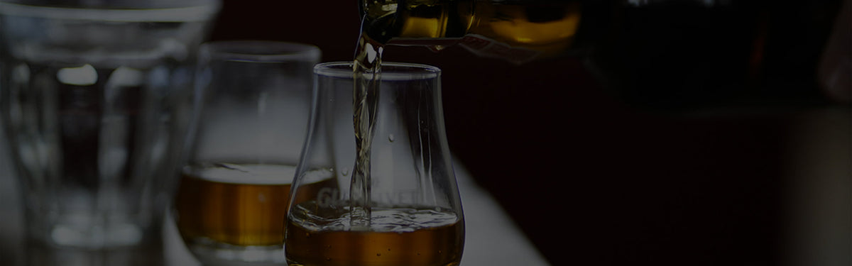Two glasses of premium Scotch whisky in tasting glasses.